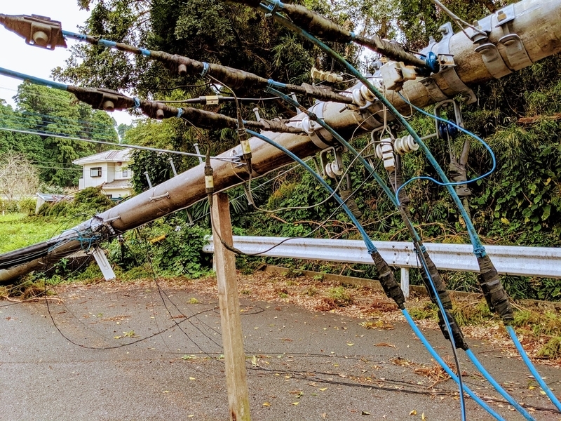 根元から折れて道路をふさぐ電柱。台風から2週間以上そのままで、近隣の住宅や信号は停電が続いた（筆者撮影）