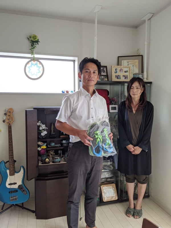 事故当日、樹生さんが履いていたシューズを手に……。和田さん宅のリビングには、今も樹生さんの愛用のベースギターをはじめ、数々の遺品が飾られている（筆者撮影）
