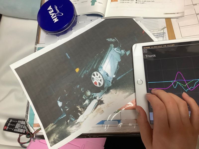 事故直後の事故車の写真を見る陽子さん。加害者が運転する車は時速150キロを超すスピードで制御不能に陥り、衝突の末、転覆した状態で停止した(石田さん提供)