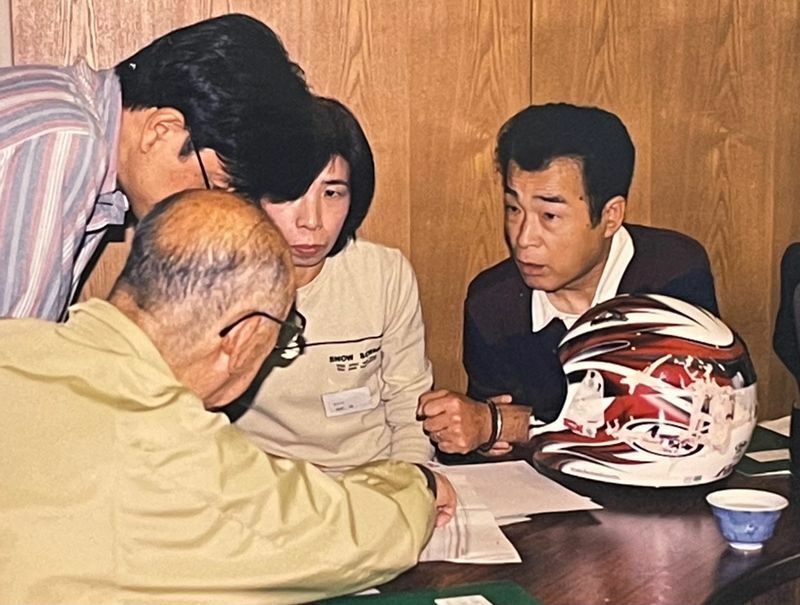 2001年、事故から約半年後に開催された「バイク事故研究会」に、敦司さんのヘルメットや衣類を持参し、交通事故鑑定の専門家に相談する楠野さん夫妻（筆者撮影）