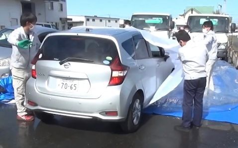 「車両用浸水防止シート」を開き、車をバックで出す場面(蔵田工業提供)