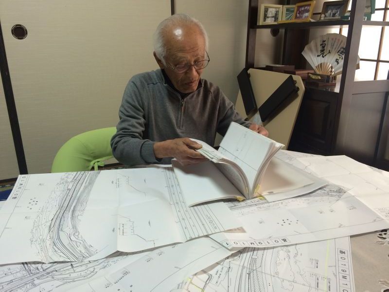 自ら入手した現場の正確な図面を広げ、加害車の動きを検証する緒方さん(筆者撮影)