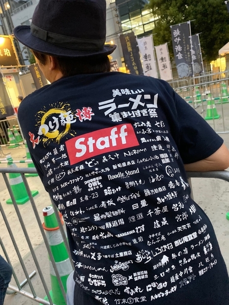 スタッフTシャツには出店する100店舗のロゴがずらりと並ぶ