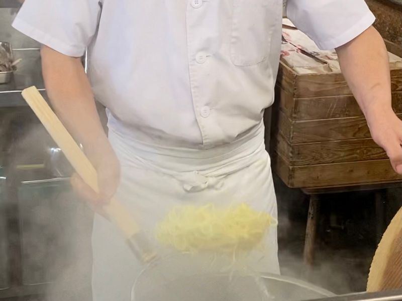 小さな茹で釜に麺を泳がせて平ざるで巧みに素早く上げる。博多ラーメンは時間との勝負だ。