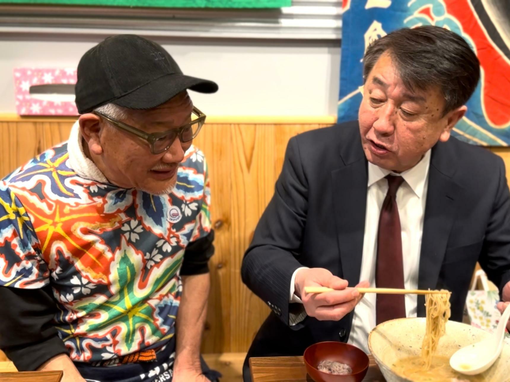 『新横浜ラーメン博物館』館長の岩岡洋志さん（右）にラーメンをふるまう河原さん。