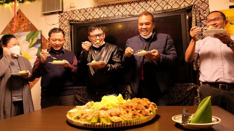 お祝いの黄色いご飯を食べる店主キキさん（右から2人目）ら＝米元文秋写す