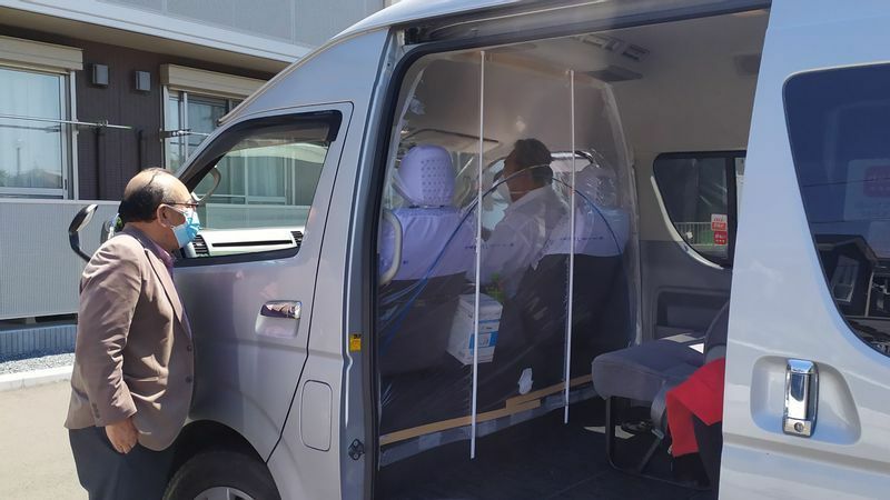 コロナ感染者を運ぶため、保健所から派遣された車を案内する坂本裕保さん（左）＝5月、米元文秋写す