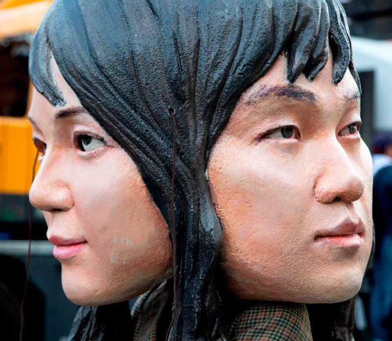 対立する韓国左派の集会では「整形前・後」の2つの顔を模した大型のお面も登場した