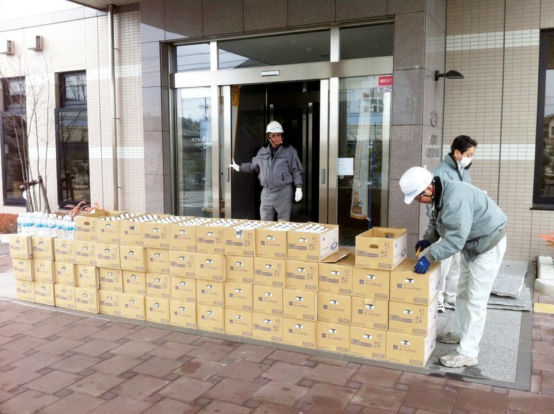 東日本大震災時、ホテルルートインいわき泉駅前店で水を配布。写真中央が永山会長（ルートイン提供）