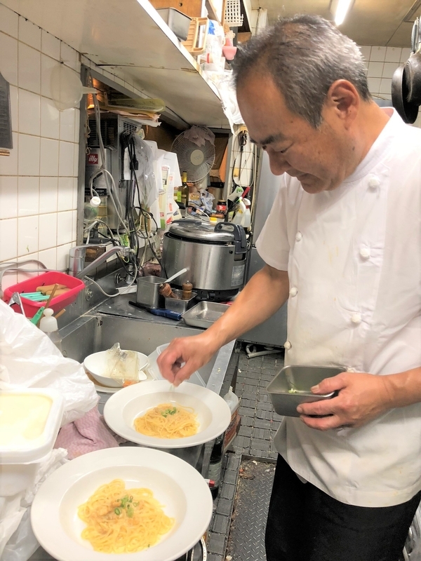 「ちょっとローマ」オーナーの佐藤義孝さん。夫婦でこの店を切り盛りして22年になる。コックがこども食堂をやるメリットは「家庭では出せない味を提供できること」。写真はローストビーフ丼と並ぶ自信メニュー「ウニのクリームパスタ」（筆者撮影）